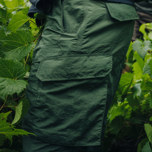Person wearing green cargo pants in a leafy environment