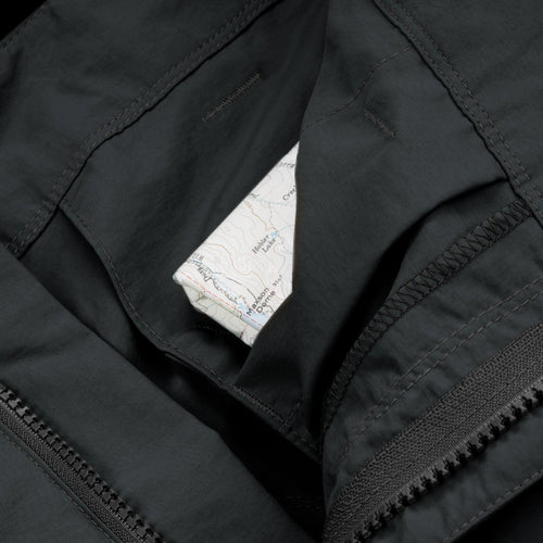 Close-up of a black jacket with a map inside the pocket on a black background